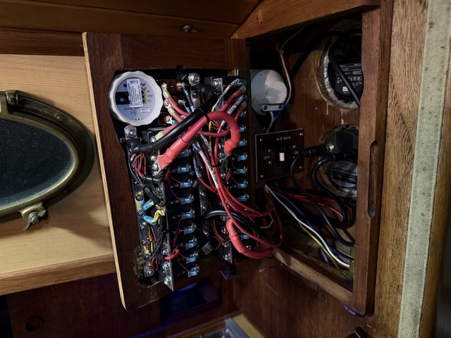 Rear of the installed electrical panel showing wiring and circuit breaker connections inside the companionway cabinet